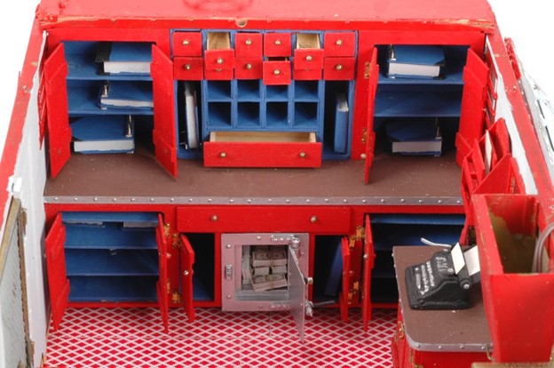 the interior view of a model wagon with shelves, open drawers, and an open safe with bundles of cash inside